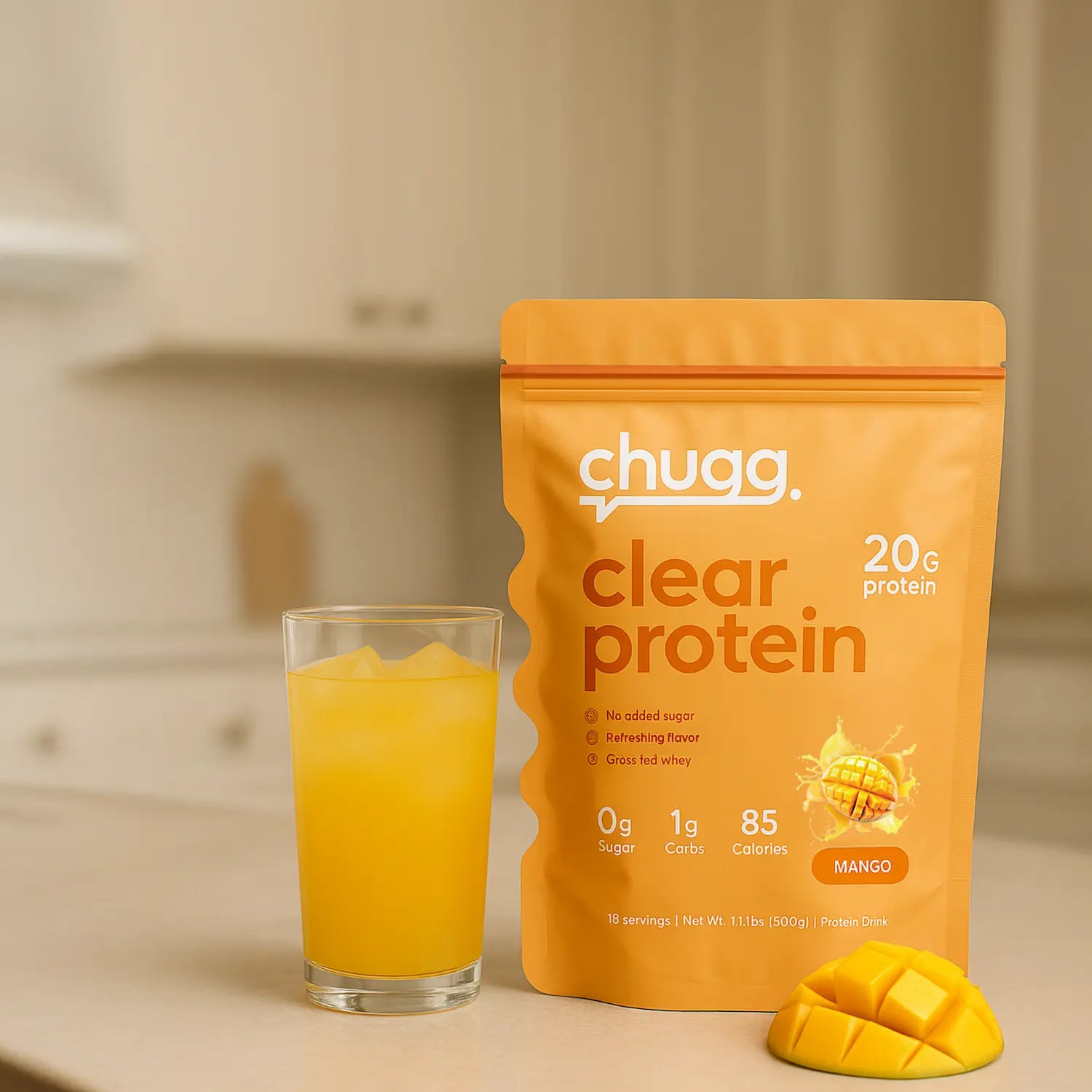 Orange Chugg Clear Protein mango pouch next to a glass of mixed protein drink and a sliced mango on a kitchen counter